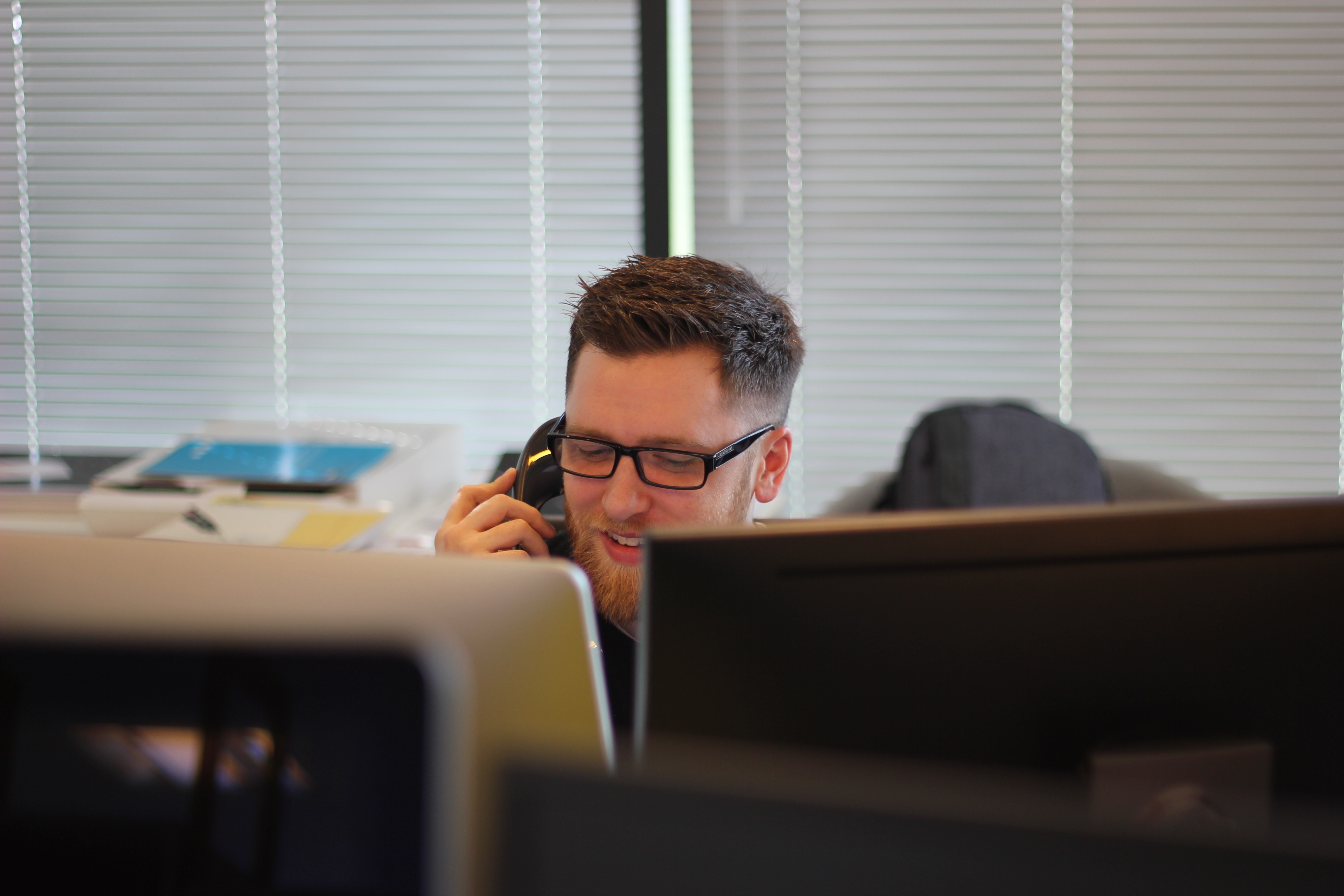 man on phone behind computer screens